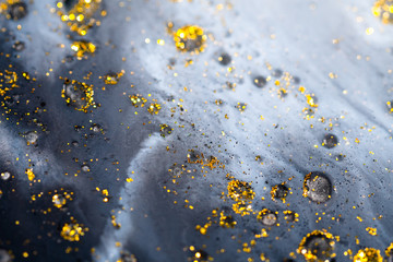 Macro Close Up Shot Of Golden Wet Glitter. Golden Space Glittering Particle Background. Golden sand...