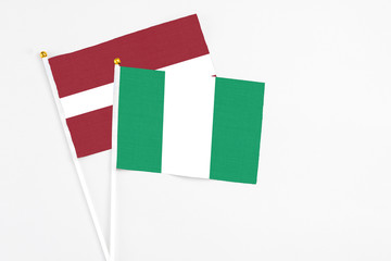 Nigeria and Latvia stick flags on white background. High quality fabric, miniature national flag. Peaceful global concept.White floor for copy space.