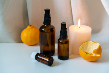 Aromatherapy products - essential oils and candle on white drapery background.