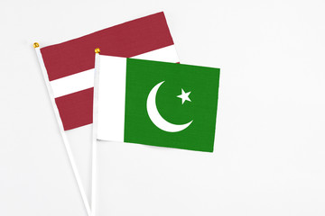 Pakistan and Latvia stick flags on white background. High quality fabric, miniature national flag. Peaceful global concept.White floor for copy space.