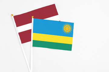 Rwanda and Latvia stick flags on white background. High quality fabric, miniature national flag. Peaceful global concept.White floor for copy space.