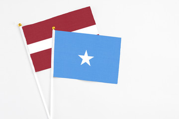Somalia and Latvia stick flags on white background. High quality fabric, miniature national flag. Peaceful global concept.White floor for copy space.