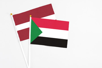 Sudan and Latvia stick flags on white background. High quality fabric, miniature national flag. Peaceful global concept.White floor for copy space.