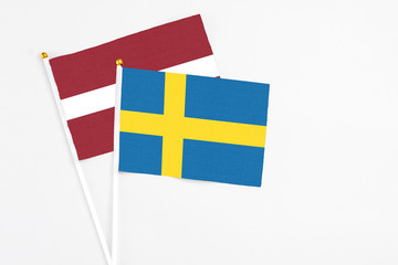 Sweden and Latvia stick flags on white background. High quality fabric, miniature national flag. Peaceful global concept.White floor for copy space.
