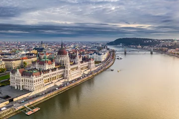 Photo sur Plexiglas Széchenyi lánchíd Budapest, Hungary - Aerial view of the beautiful Parliament of Hungary at sunset with golden lights and sightseeing boats on River Danube. Szechenyi Chain Bridge, St. Stephen's Basilica at background