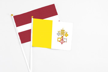 Vatican City and Latvia stick flags on white background. High quality fabric, miniature national flag. Peaceful global concept.White floor for copy space.