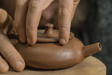 potter sculpts a chinese teapot from yixing purple clay