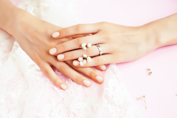 woman hands with manicure and wedding ring among white lace and little flowers