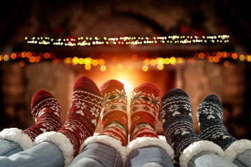 Blurred background of chrsitmas fireplace.Orange color of warm light of fire.Woman legs with socks...