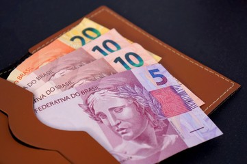 Brazilian banknotes on brown wallet. Concept of economy, savings and inflation. 