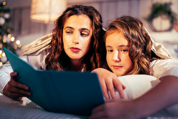 young pretty girls in bed at Christmass morning, happy family smiling lifestyle at holiday reading book