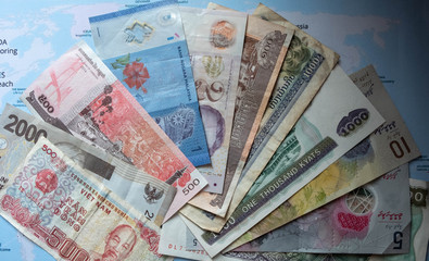 Bank notes or currencies of many countries but not new condition and arranged as a fan, can't to see the completion of details. It's placed on the world map with natural window light from one side