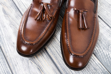 Brown classic loafers with tassels stand on a wooden stand