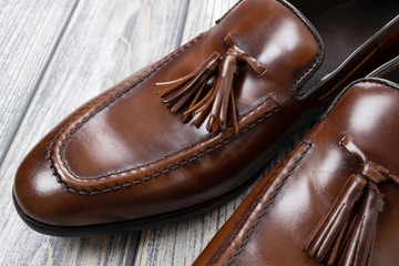 Brown classic loafers with tassels stand on a wooden stand