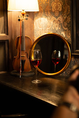 a glass a mirror and an old violin on the bar - obrazy, fototapety, plakaty