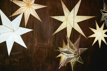 Decorative stars bulb lights on brown wood wall, copy space. Christmas background with stars and garland