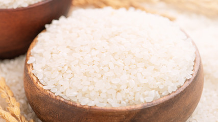 Fototapeta na wymiar Raw white polished milled edible rice crop on white background in brown bowl, organic agriculture design concept. Staple food of Asia, close up.