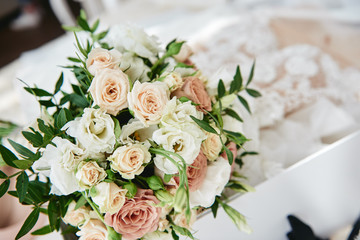Close up of bridal bouquet of beige and pink roses with wedding dress on background, copy space. Wedding concept