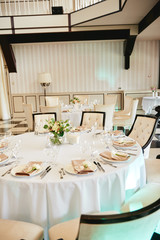 Table setting with blank guest card, white plate with beige serviette, rose, heart and cutlery on table, copy space. Place setting at wedding reception. Table served for wedding banquet in restaurant