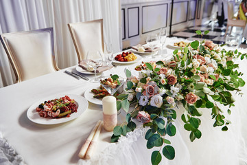Lush floral arrangement on wedding table. Wedding presidium in restaurant, copy space. Banquet...