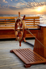 Old wooden ship's helm on background of sea sunset
