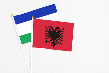 Obraz premium Albania and Lesotho stick flags on white background. High quality fabric, miniature national flag. Peaceful global concept.White floor for copy space.