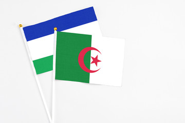 Algeria and Lesotho stick flags on white background. High quality fabric, miniature national flag. Peaceful global concept.White floor for copy space.