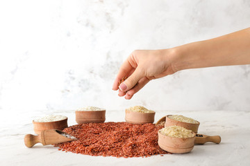 Female hand with different raw rice on white background