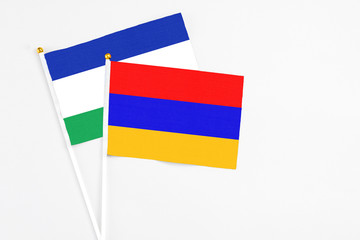 Armenia and Lesotho stick flags on white background. High quality fabric, miniature national flag. Peaceful global concept.White floor for copy space.