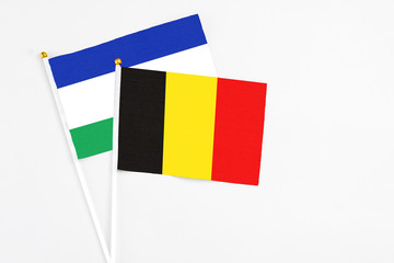 Belgium and Lesotho stick flags on white background. High quality fabric, miniature national flag. Peaceful global concept.White floor for copy space.