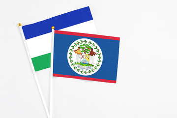 Belize and Lesotho stick flags on white background. High quality fabric, miniature national flag. Peaceful global concept.White floor for copy space.