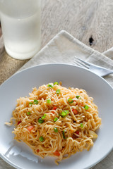 The noodles are in a round white plate placed on a wooden table.noodle concept with copy space