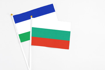 Bulgaria and Lesotho stick flags on white background. High quality fabric, miniature national flag. Peaceful global concept.White floor for copy space.