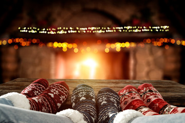 Blurred background of chrsitmas fireplace.Orange color of warm light of fire.Woman legs with socks and jeans.Copy space.Free place for your decoration.Cold winter december night.Christmas Eve party.