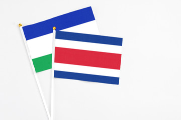 Costa Rica and Lesotho stick flags on white background. High quality fabric, miniature national flag. Peaceful global concept.White floor for copy space.