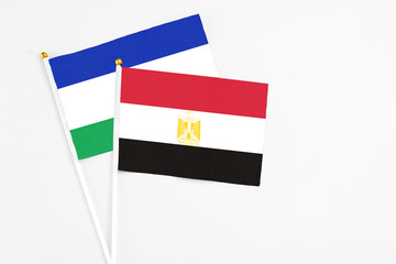 Egypt and Lesotho stick flags on white background. High quality fabric, miniature national flag. Peaceful global concept.White floor for copy space.