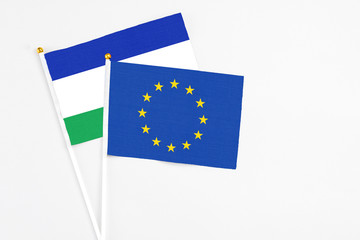 European Union and Lesotho stick flags on white background. High quality fabric, miniature national flag. Peaceful global concept.White floor for copy space.