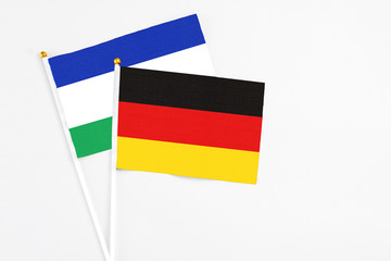 Germany and Lesotho stick flags on white background. High quality fabric, miniature national flag. Peaceful global concept.White floor for copy space.
