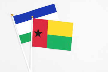 Guinea Bissau and Lesotho stick flags on white background. High quality fabric, miniature national flag. Peaceful global concept.White floor for copy space.