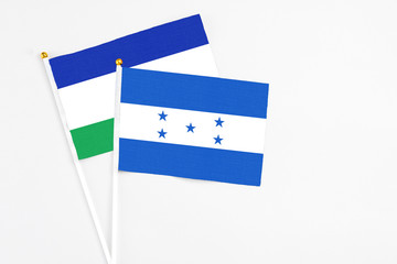 Honduras and Lesotho stick flags on white background. High quality fabric, miniature national flag....
