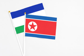 North Korea and Lesotho stick flags on white background. High quality fabric, miniature national flag. Peaceful global concept.White floor for copy space.