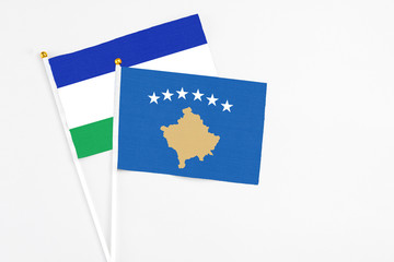 Kosovo and Lesotho stick flags on white background. High quality fabric, miniature national flag....