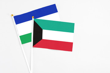Kuwait and Lesotho stick flags on white background. High quality fabric, miniature national flag. Peaceful global concept.White floor for copy space.