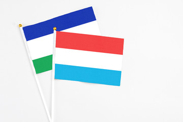 Luxembourg and Lesotho stick flags on white background. High quality fabric, miniature national flag. Peaceful global concept.White floor for copy space.