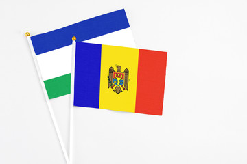 Moldova and Lesotho stick flags on white background. High quality fabric, miniature national flag. Peaceful global concept.White floor for copy space.
