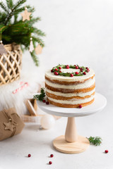 Christmas composition. Festive cake decorated with rosemary and cranberries, gifts and fir tree on...