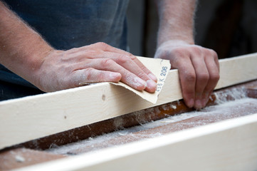 carpenter polishes wood with sandpaper