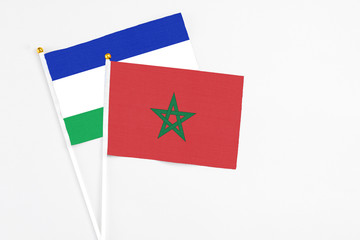 Morocco and Lesotho stick flags on white background. High quality fabric, miniature national flag. Peaceful global concept.White floor for copy space.