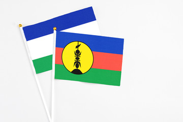 New Caledonia and Lesotho stick flags on white background. High quality fabric, miniature national...