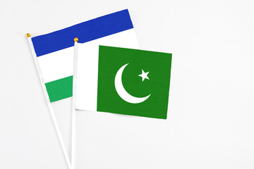 Pakistan and Lesotho stick flags on white background. High quality fabric, miniature national flag....